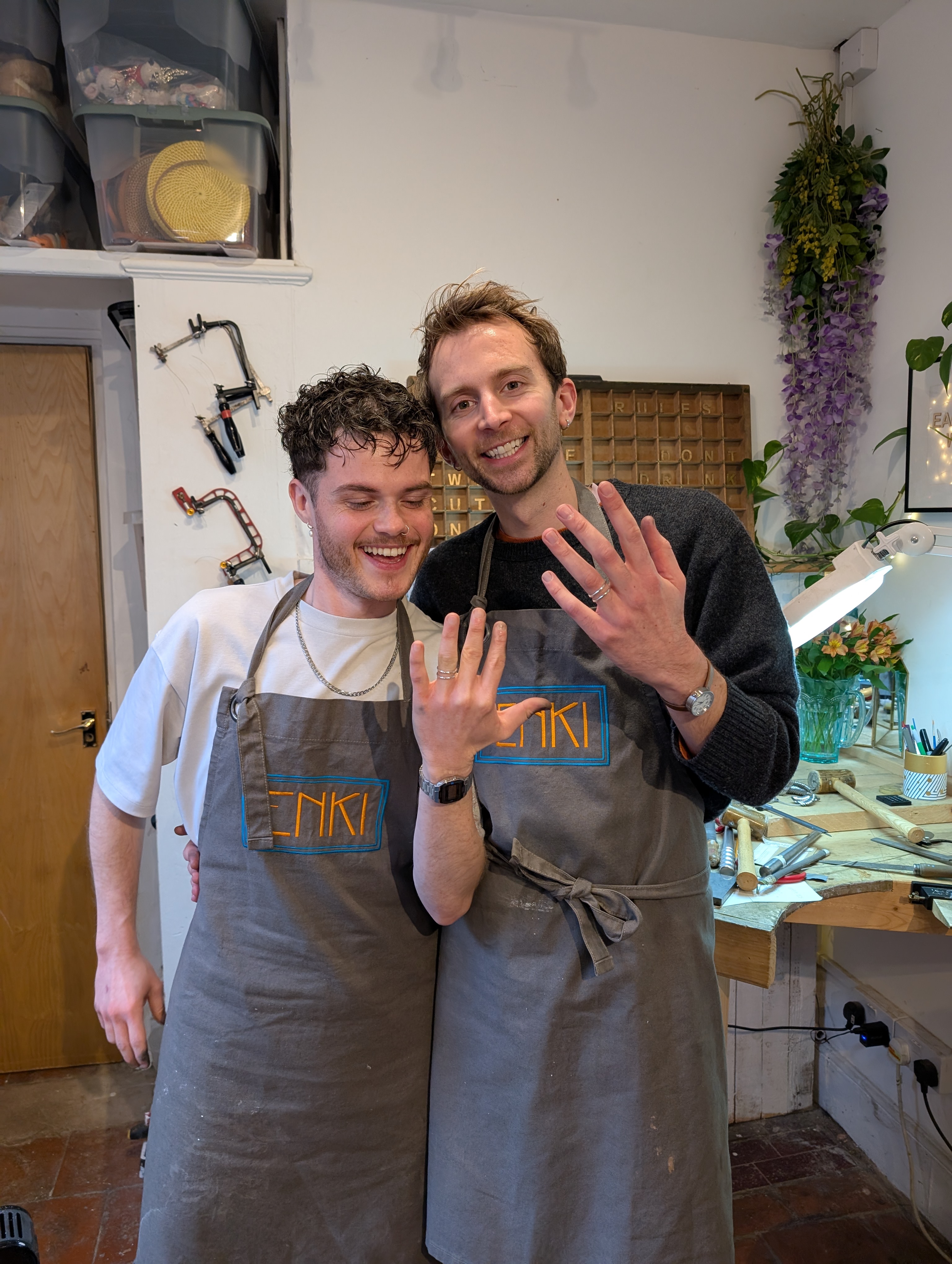 a couple holding their hands up sporting their new rings