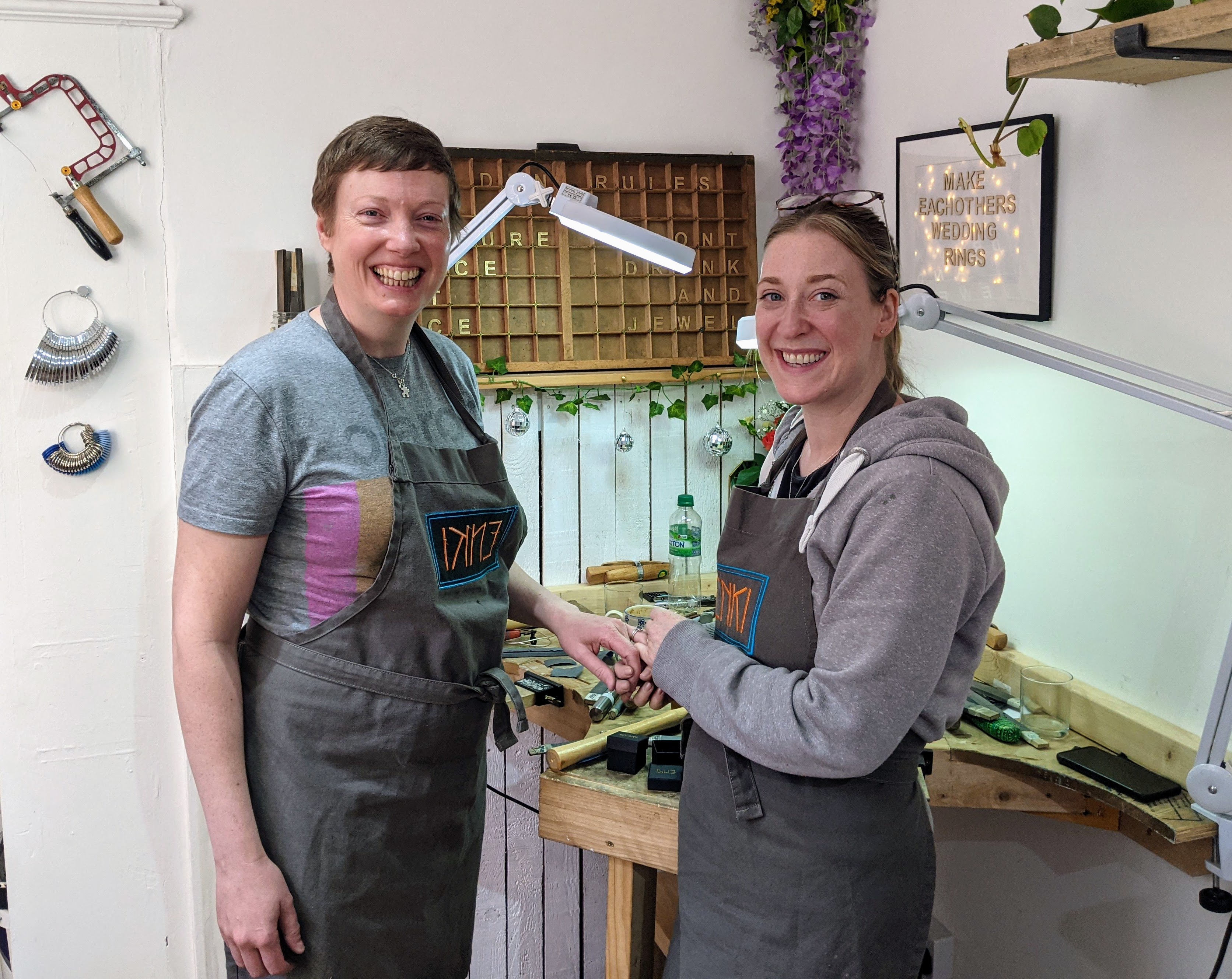 a couple smiling as they stand and inspect their rings